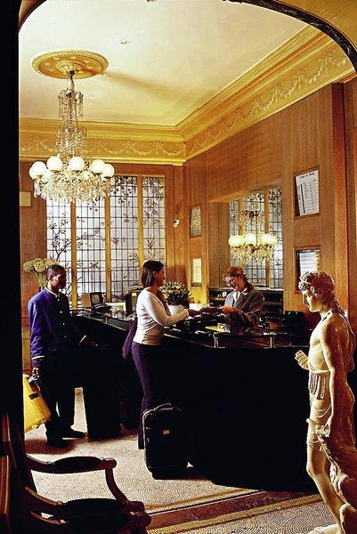 Rezeption im Best Western Hotel Ronceray Opera mit einer Statue, Rezeptionsmitarbeitern und Gästen.