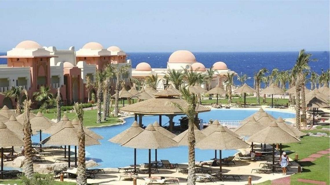 Außenbereich des Serenity Alpha Beach Resorts mit Pool, Sonnenschirmen und Blick auf das Meer.