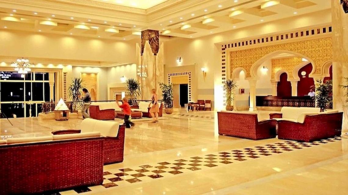 Hotellobby von Serenity Alpha Beach mit roten Sofas, gemustertem Boden und hohen Decken.