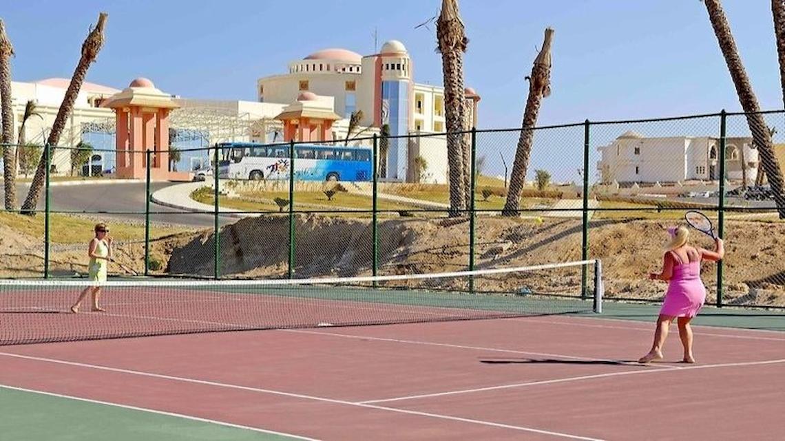 Zwei Frauen spielen Tennis auf einem Tennisplatz im Serenity Alpha Beach Hotel.