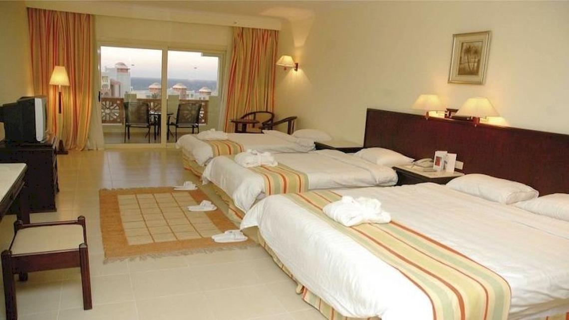 Hotelzimmer im Serenity Alpha Beach mit drei Betten, Fernseher, und Balkonzugang.
