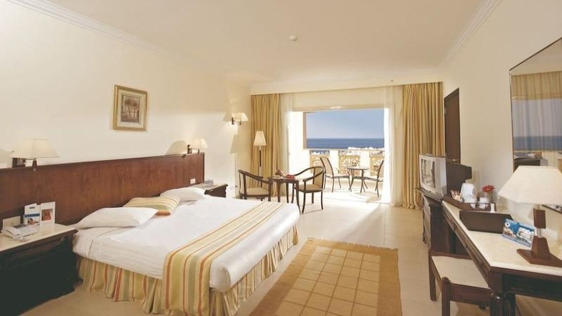 Hotelzimmer im Serenity Alpha Beach mit Blick auf den Ozean, Doppelbett, Balkon mit Möbeln und Fernseher.