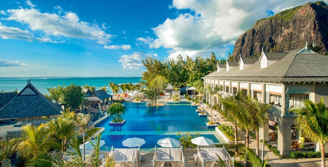 Außenbereich des JW Marriott Mauritius Resorts mit Pool und Blick auf das Meer und einen Berg.