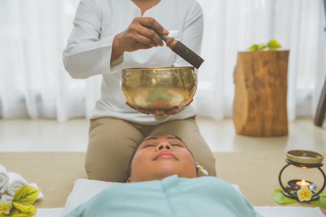 Massage im JW Marriott Mauritius Resort, eine Person wird massiert, während eine andere eine Glocke hält.