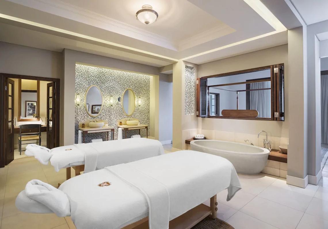 Spa-Behandlungsraum im JW Marriott Mauritius Resort mit zwei Massageliegen und Badewanne.