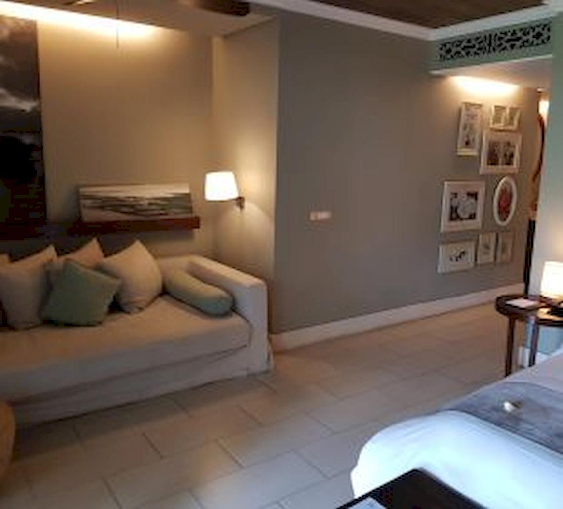 Schlafzimmer im JW Marriott Mauritius Resort mit Bett, Sofa, Nachttisch und dekorierten Wänden.