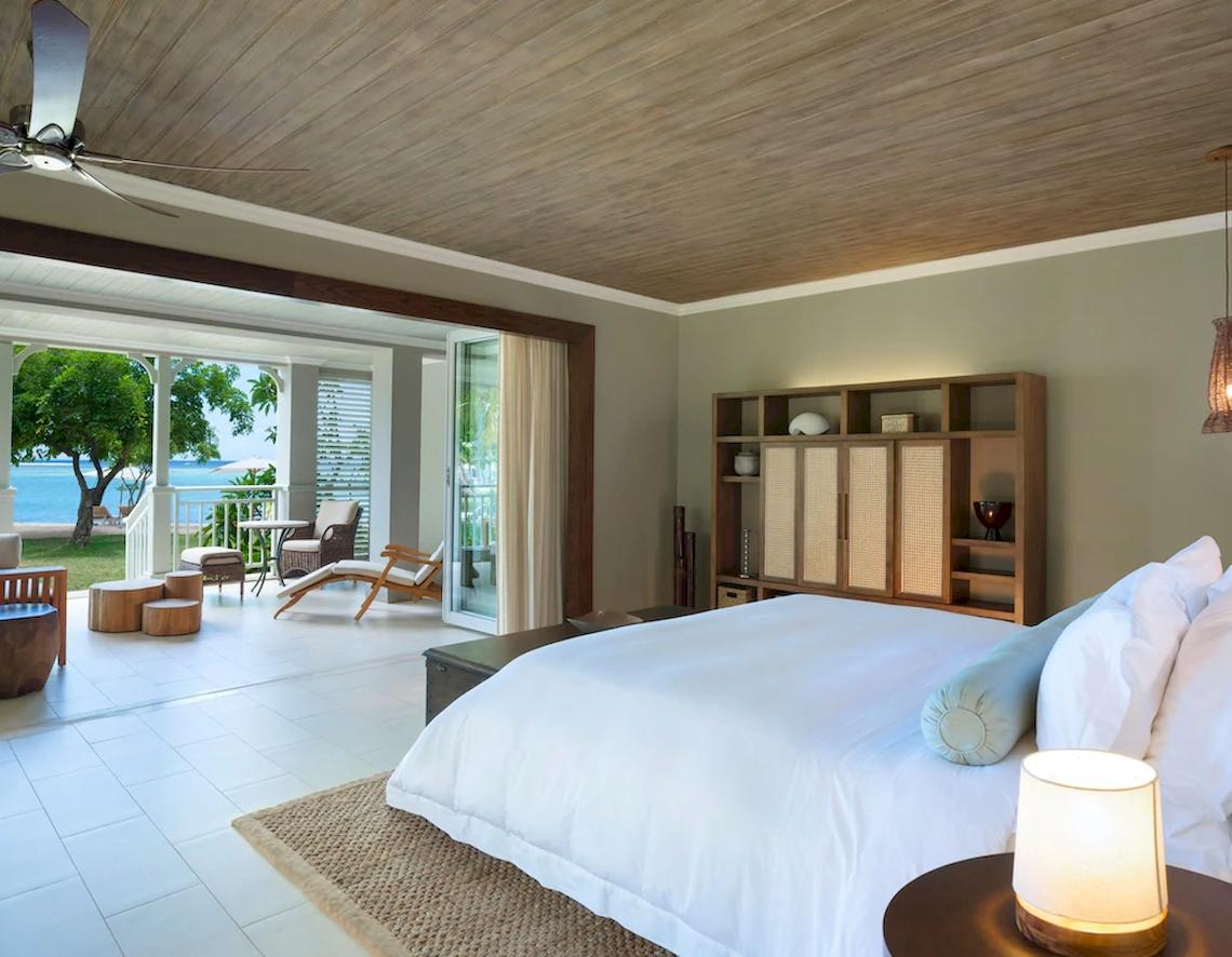 Schlafzimmer im JW Marriott Mauritius Resort mit Blick auf den Ozean und Holzmöbeln.