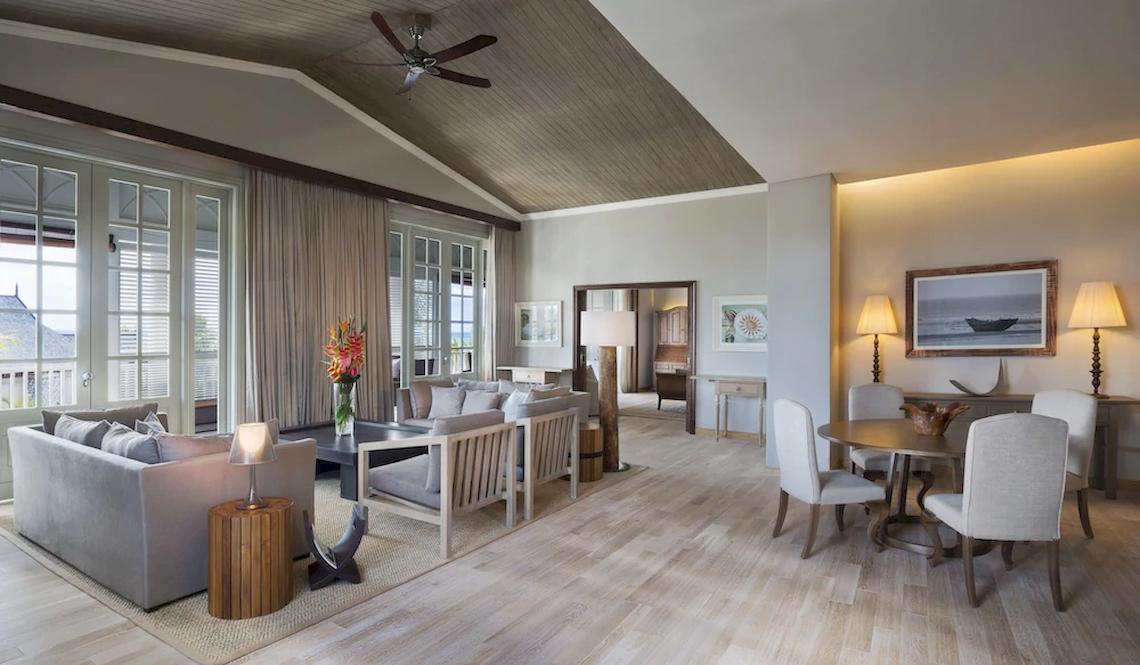 Wohnbereich im JW Marriott Mauritius Resort mit Holzboden, Sofas, Esstisch und Fenstern.
