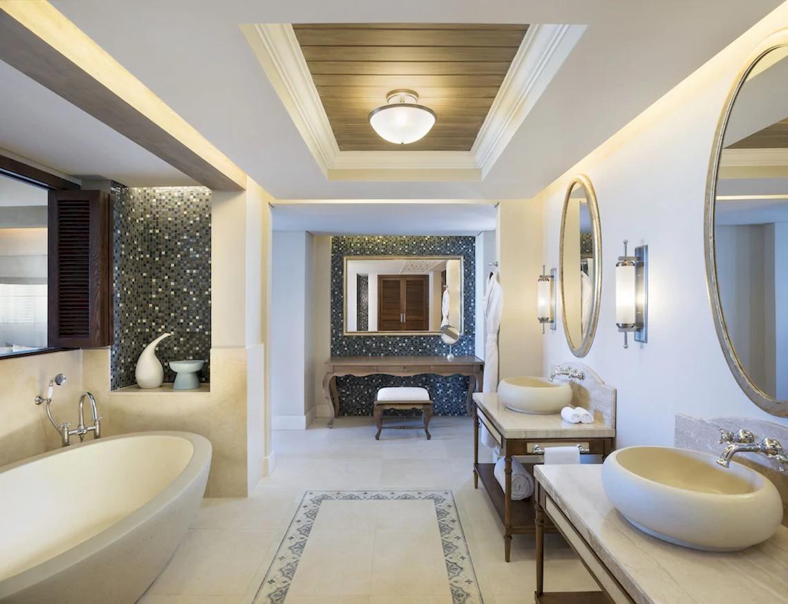 Innenansicht eines Badezimmers im JW Marriott Mauritius Resort mit Badewanne, Waschbecken und Spiegel.