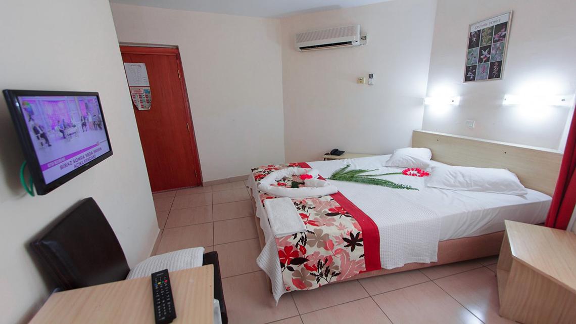 Ein Hotelzimmer im Malhun Hotel mit einem Doppelbett, Fernseher an der Wand, und einem Tisch mit Fernbedienung.
