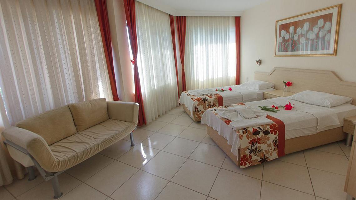 Hotelzimmer im Malhun Hotel mit zwei Betten, einem Sofa und weißem Teppichboden.