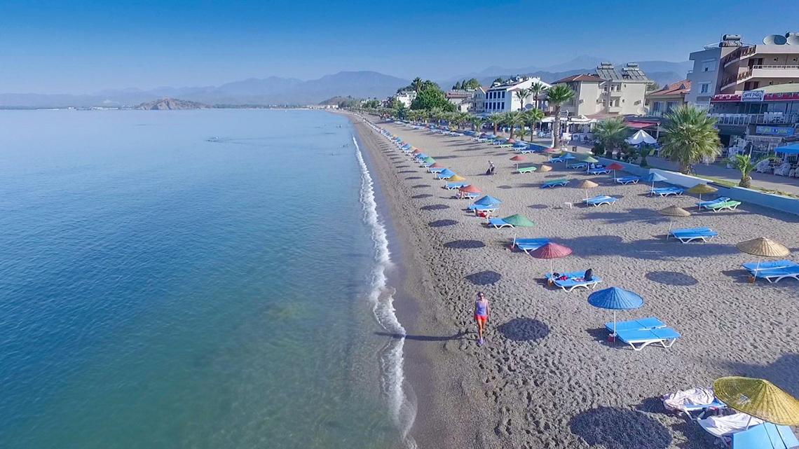 Luftaufnahme der Malhun Hotel Strand mit vielen Liegen und Sonnenschirmen am Meer.