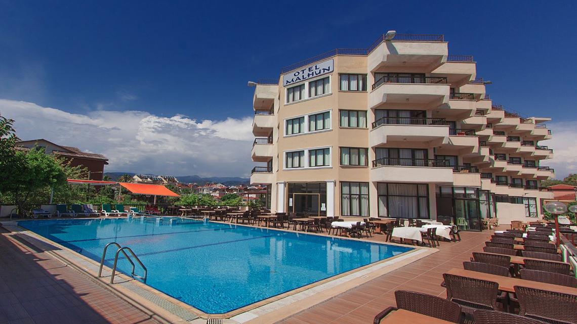Außenbereich des Malhun Hotels mit Swimmingpool und umliegenden Terrassen und Tischen.