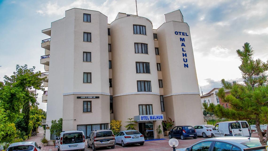 Außenansicht des Malhun Hotels, ein modernes Gebäude mit mehreren Stockwerken und Parkplätzen vor dem Gebäude.