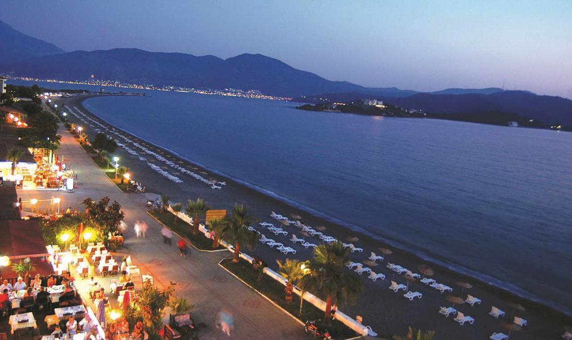 Abendlicher Blick auf den Strand des Malhun Hotels mit vielen Liegen und Palmen.