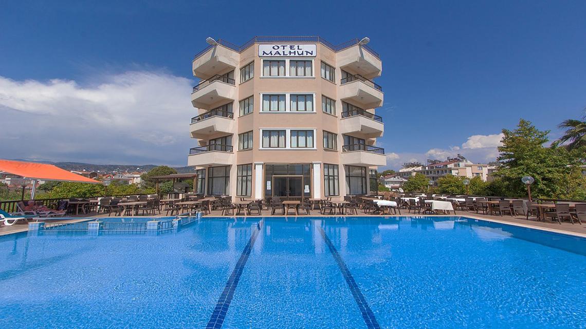 Außenansicht des Malhun Hotels mit Swimmingpool und Sonnenschirmen am Rand.