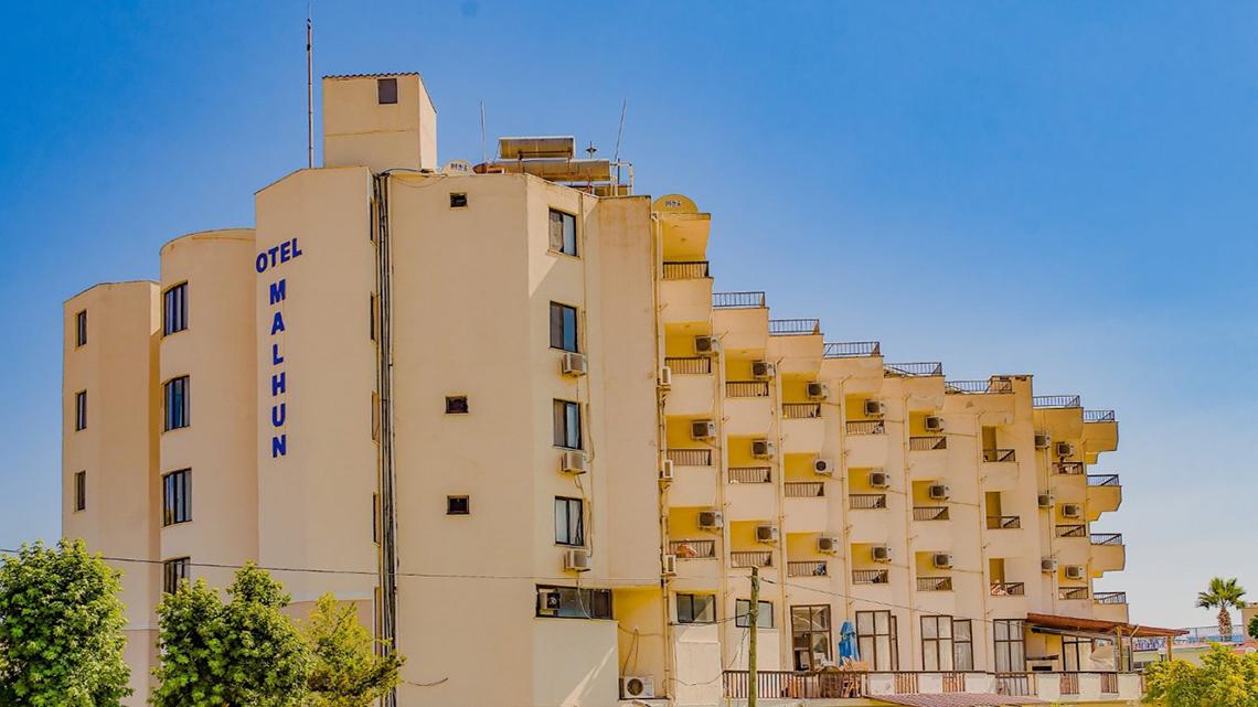Außenansicht des Malhun Hotels, ein großes gelbes Gebäude mit vielen Fenstern und Balkonen.
