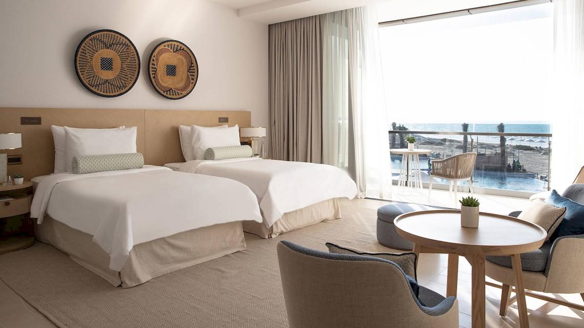 Doppelbettzimmer im Jumeirah at Saadiyat Island Resort mit Blick auf den Ozean und eine Terrasse.