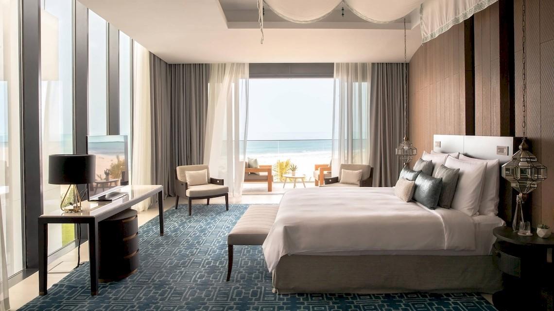 Schlafzimmer im Jumeirah at Saadiyat Island Resort mit Meerblick, großem Bett, Schreibtisch und Lampen.