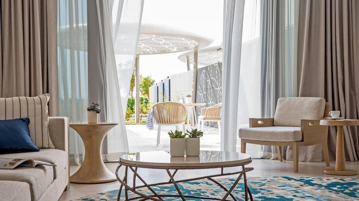 Wohnzimmer im Jumeirah at Saadiyat Island Resort mit moderner Einrichtung und offenem Zugang zur Terrasse.