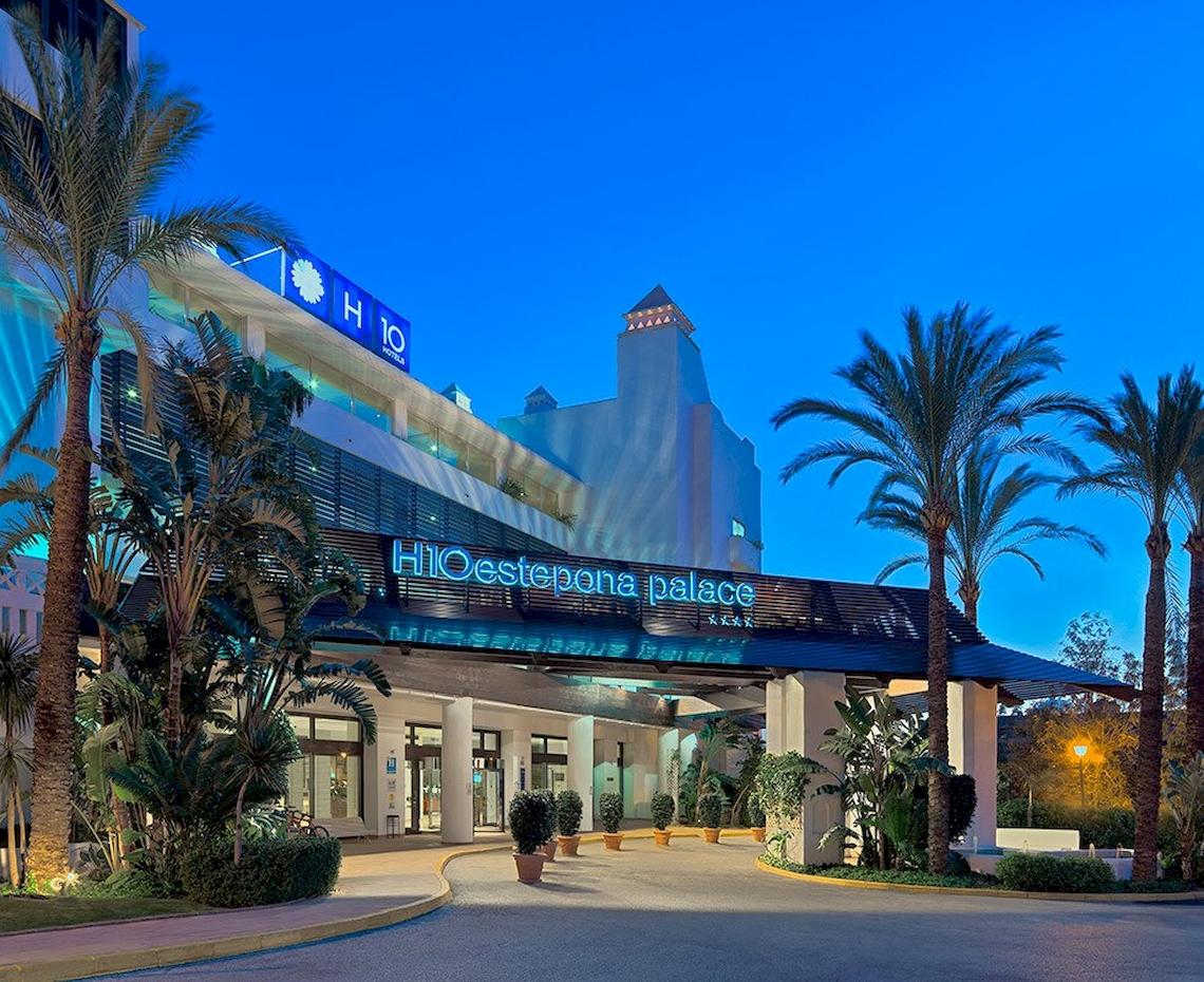 Eingang des H10 Estepona Palast Hotels mit Palmen und Beleuchtung