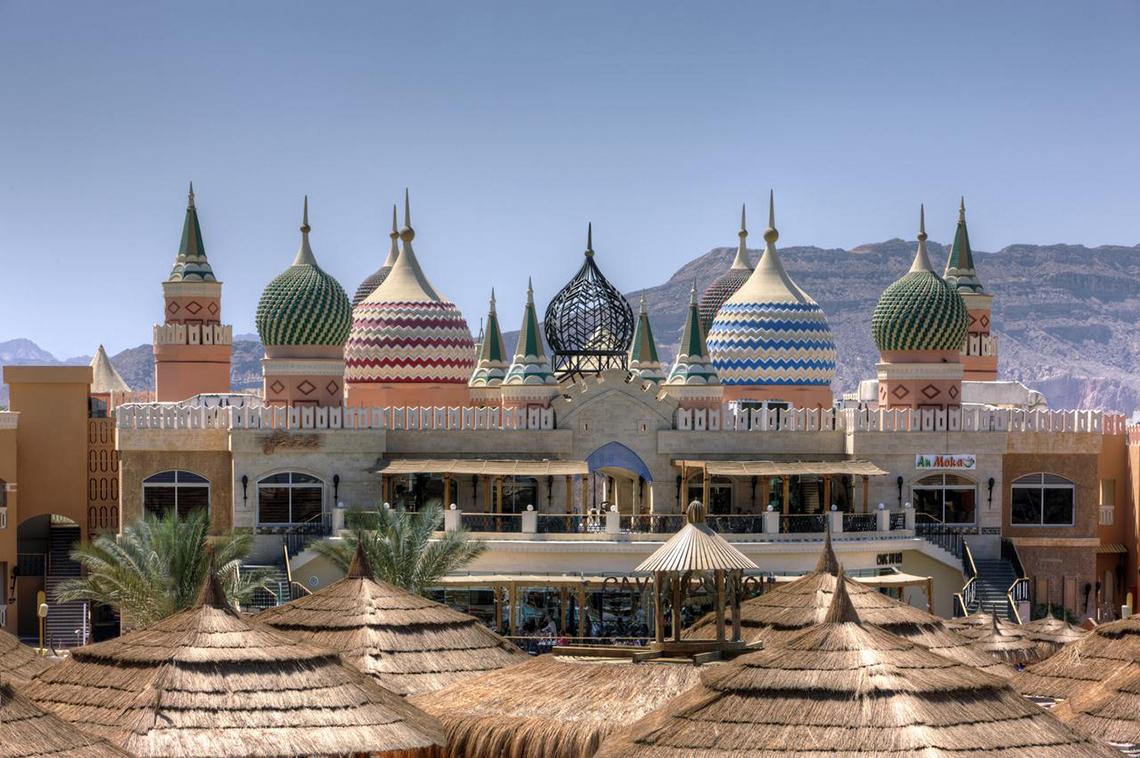 Außenansicht des Pickalbatros Aqua Blu Resort in Sharm mit bunten Kuppeldächern und Bergen im Hintergrund.
