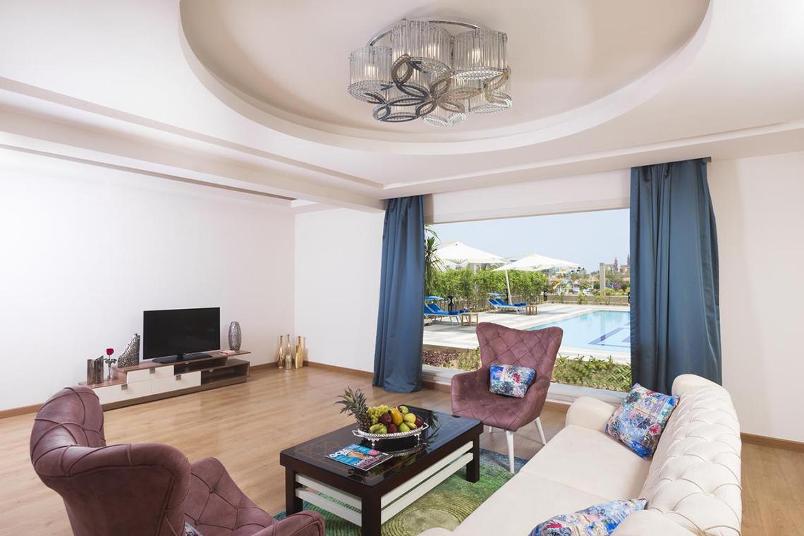 Innenansicht des Wohnzimmers im Pickalbatros Aqua Blu Resort mit moderner Einrichtung und Blick auf den Pool.