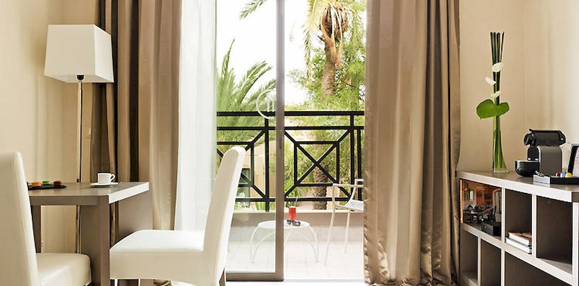 Zimmer im Barcelo Palmeraie Hotel mit Blick auf einen Balkon und Außenbereich.