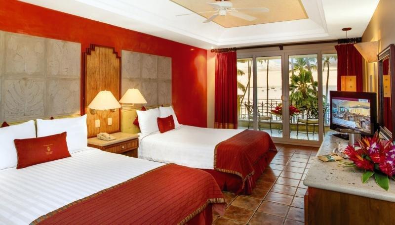 Doppelzimmer im Tamarindo Diria Beach Resort mit zwei Betten, rotem Dekor, Balkon und Meerblick.