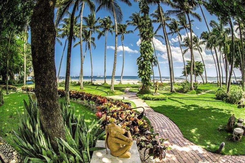 Außenbereich des Tamarindo Diria Beach Resort mit Blick auf den Strand und Palmen.