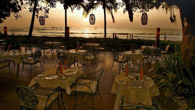 Außenterrasse des Tamarindo Diria Beach Resorts mit Blick auf den Ozean und Sonnenuntergang.