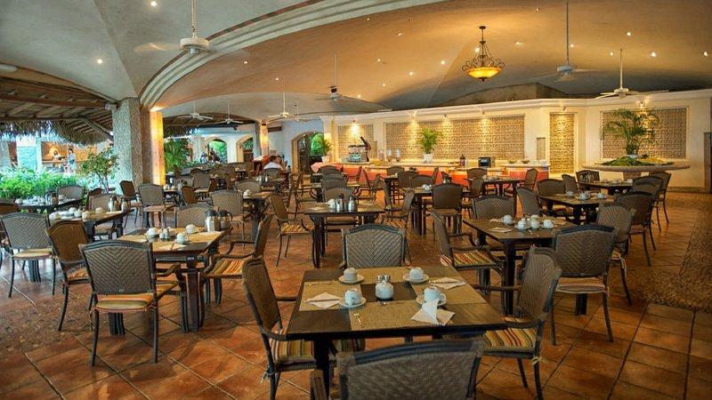 Innenansicht des Restaurants im Tamarindo Diria Beach Resort mit runden Tischen und Stühlen.