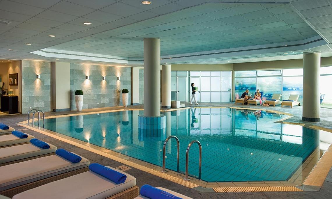 Innenpool des Mediterranean Beach Hotel in Zypern mit Loungebereich und Personen