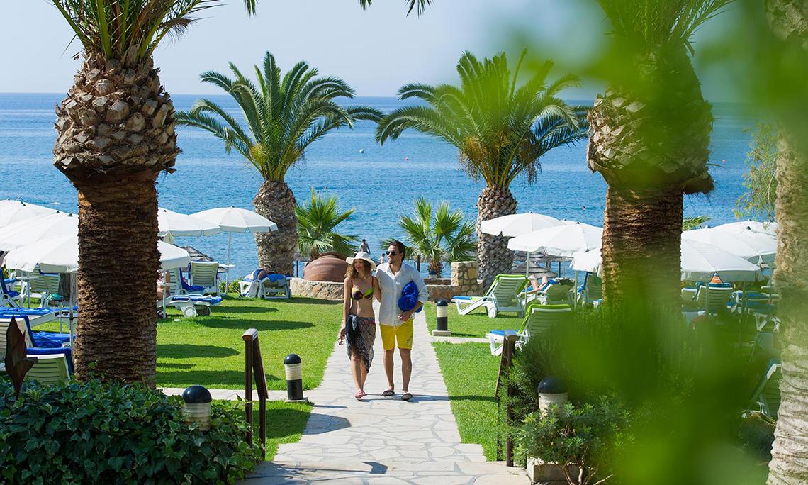 Paar am Mittelmeer Beach Hotel in Zypern entlang des Strandes spazierend