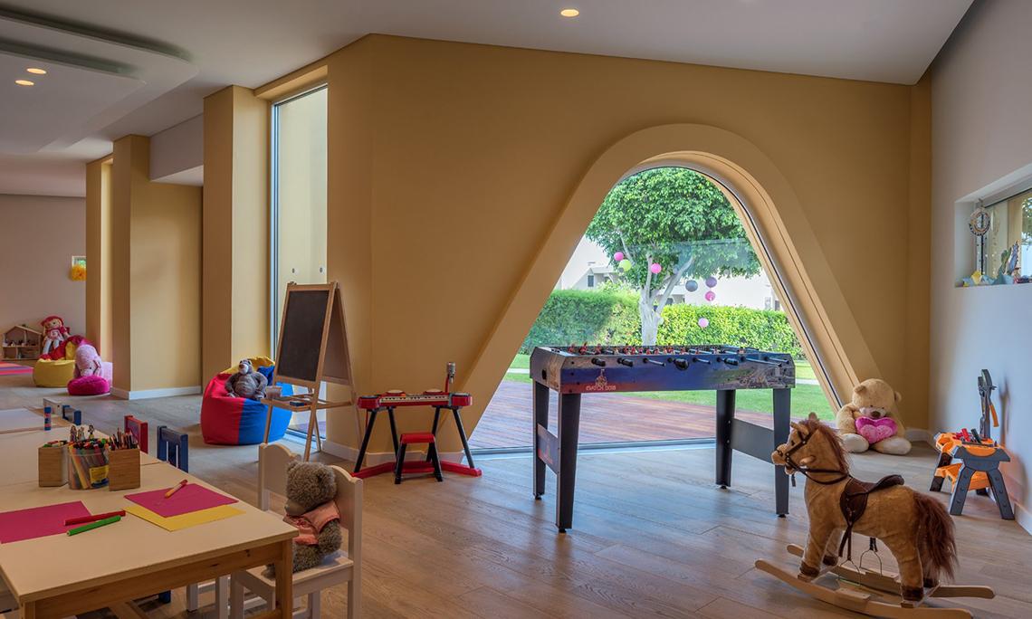 Kinderzimmer im Mediterranean Beach Hotel mit Tisch, Stühlen und Spielzeug.