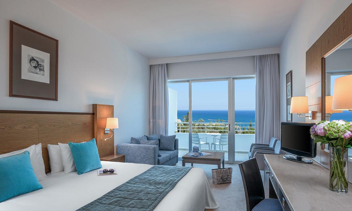 Hotelzimmer mit Meerblick im Mediterranean Beach Hotel mit großem Bett und Wohnzimmerbereich
