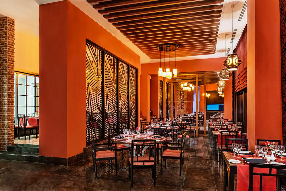 Innenansicht eines Hotels mit Restaurantbereich, Tischen und Stühlen, gedeckten Tischen und geometrischen Mustern an den Wänden.