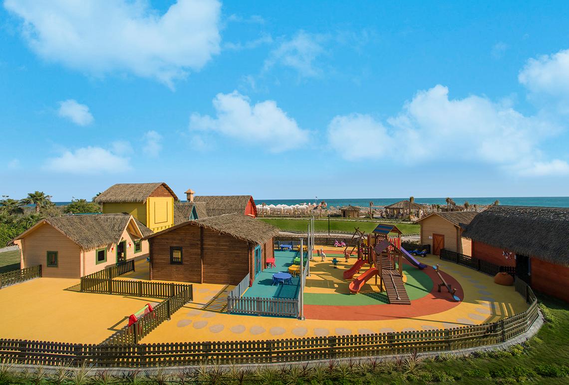 Außenansicht des Kinderspielplatzes im Aska Lara Resort & Spa mit bunten Spielgeräten und Hütten.