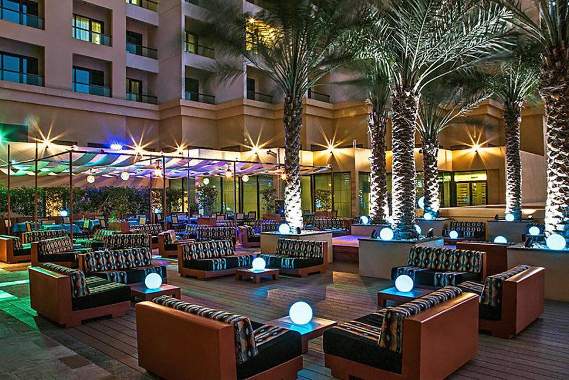Loungebereich des JA Ocean View Hotels mit illuminierten Palmen und Sofas.