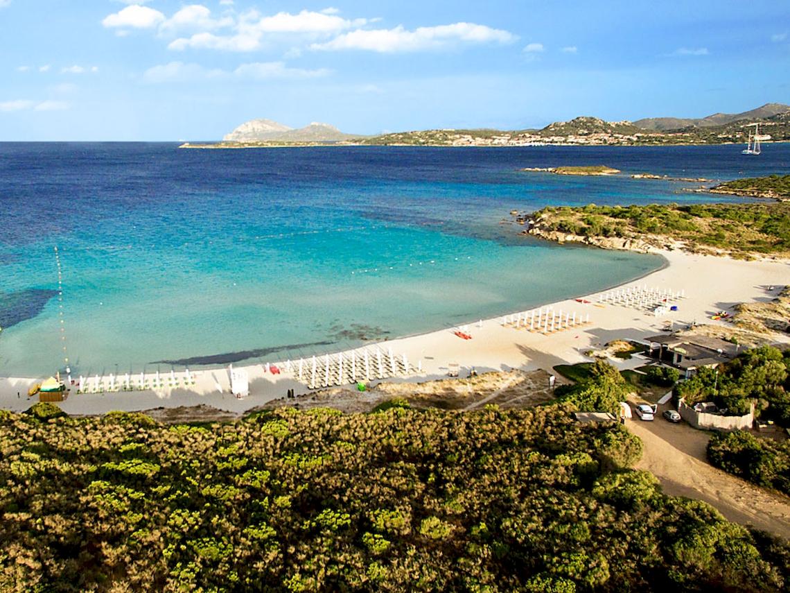 Luftaufnahme des Colonna Hotel Du Golf Strands mit blauem Wasser und weißen Sonnenliegen
