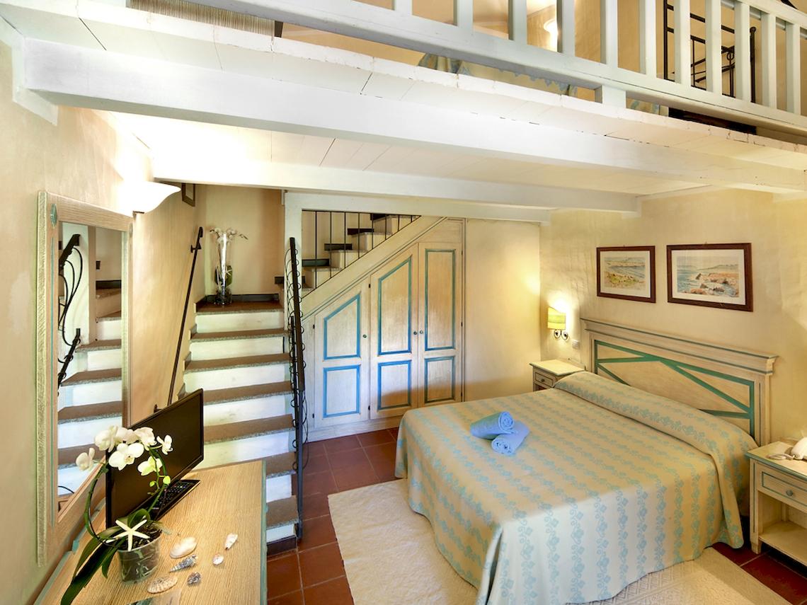 Schlafzimmer mit Bett und Stiege im Hotel Colonna Du Golf