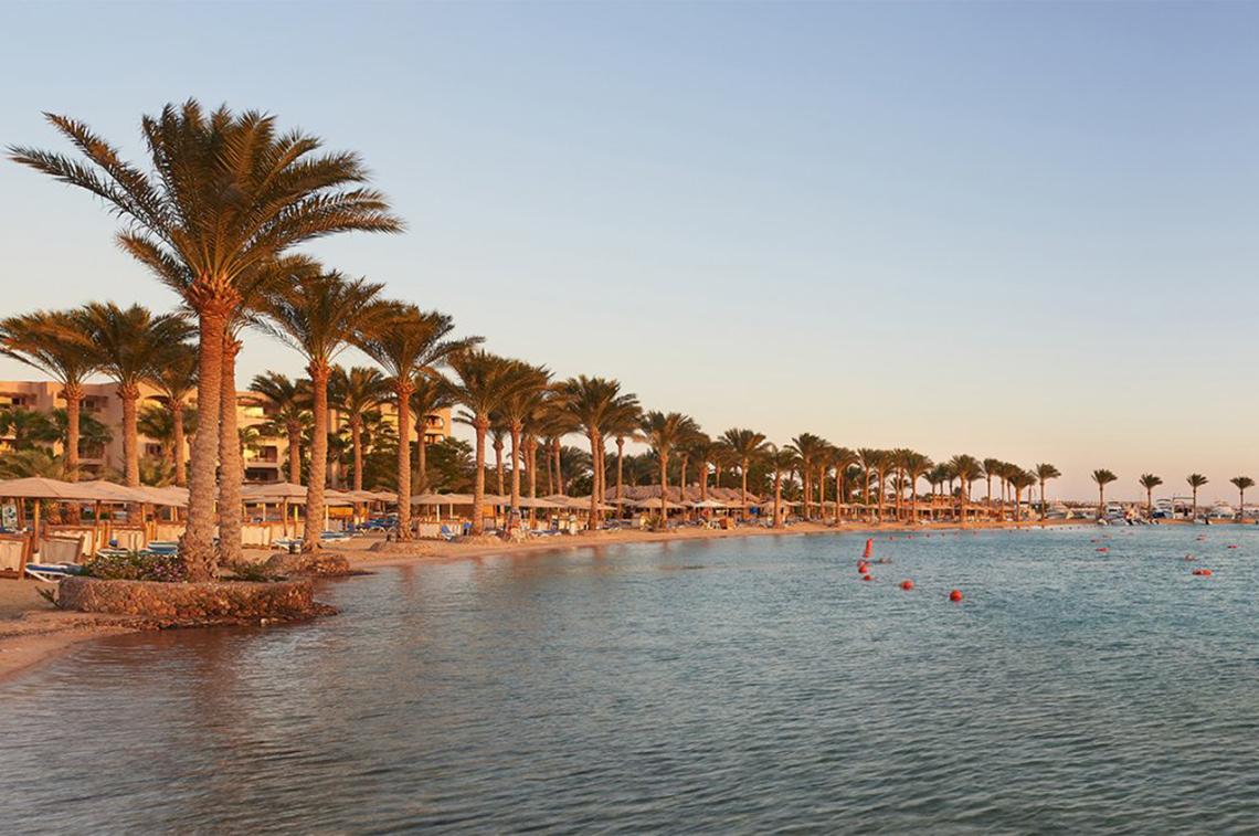 Strand des Continental Hotel Hurghada mit Palmen und Wasser
