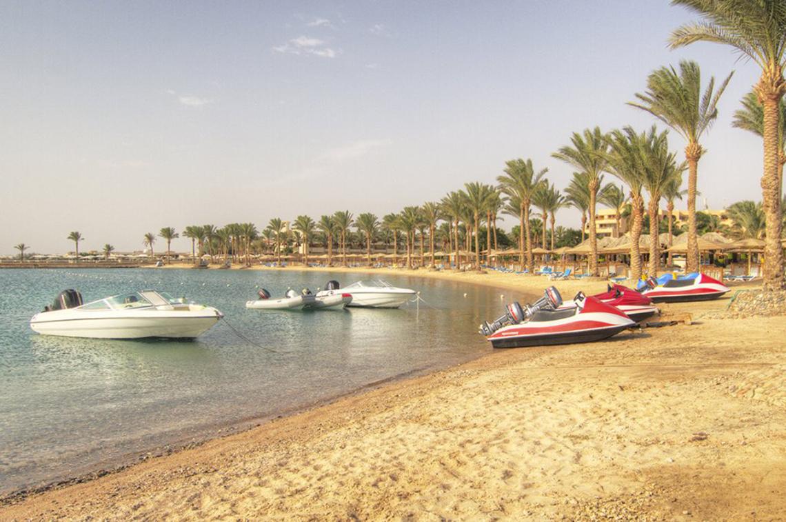 Strand des Continental Hotel Hurghada mit mehreren geparkten Booten und Palmen
