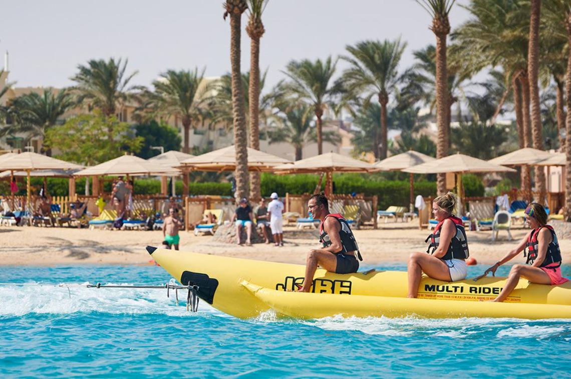 Drei Personen sitzen auf einem gelben Banana Boot am Strand des Continental Hotels Hurghada.
