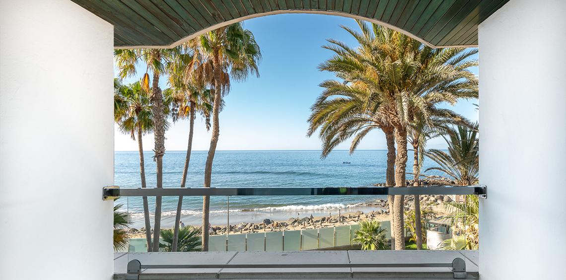 Aussicht auf den Strand mit Palmen vom Hotel Faro, a Lopesan Collection Hotel.
