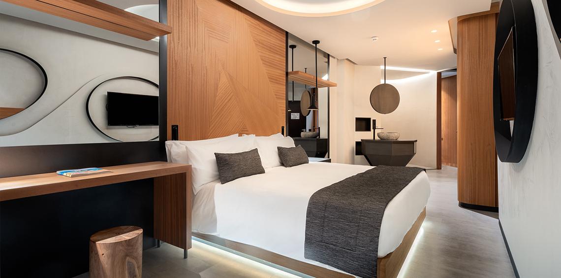 Hotelzimmer im Faro, Lopesan Collection Hotel mit weißem Bett, Holzwänden und modernem Design.