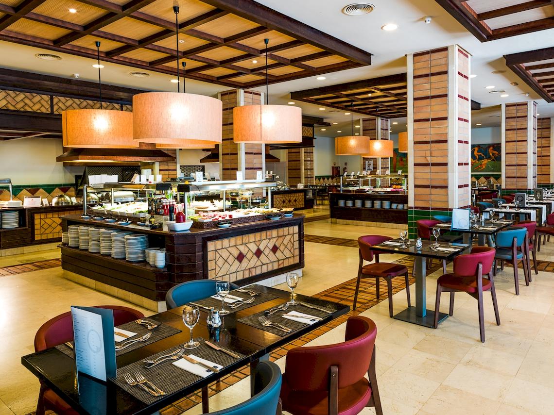 Innenansicht des Restaurants im H10 Estepona Palace mit Buffet und gedeckten Tischen.
