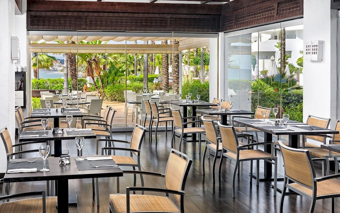 Innenansicht des Restaurants im H10 Estepona Palace mit Blick auf den Garten und das Meer.