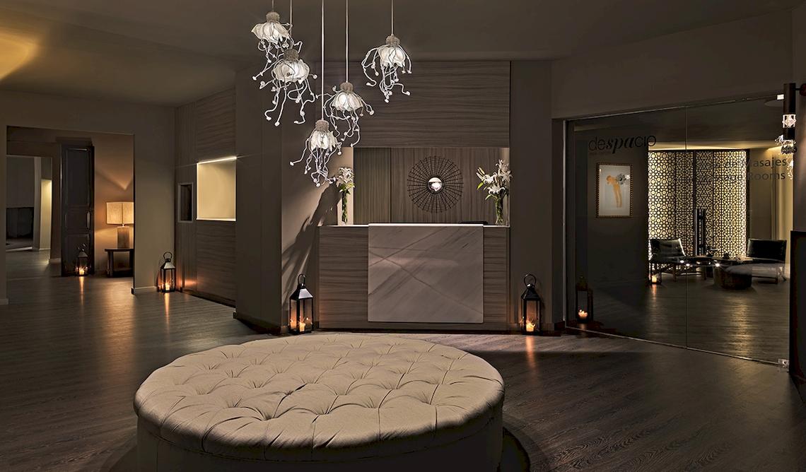 Empfangshalle des H10 Estepona Palace mit modernen Lampen und einem großen Sofa.