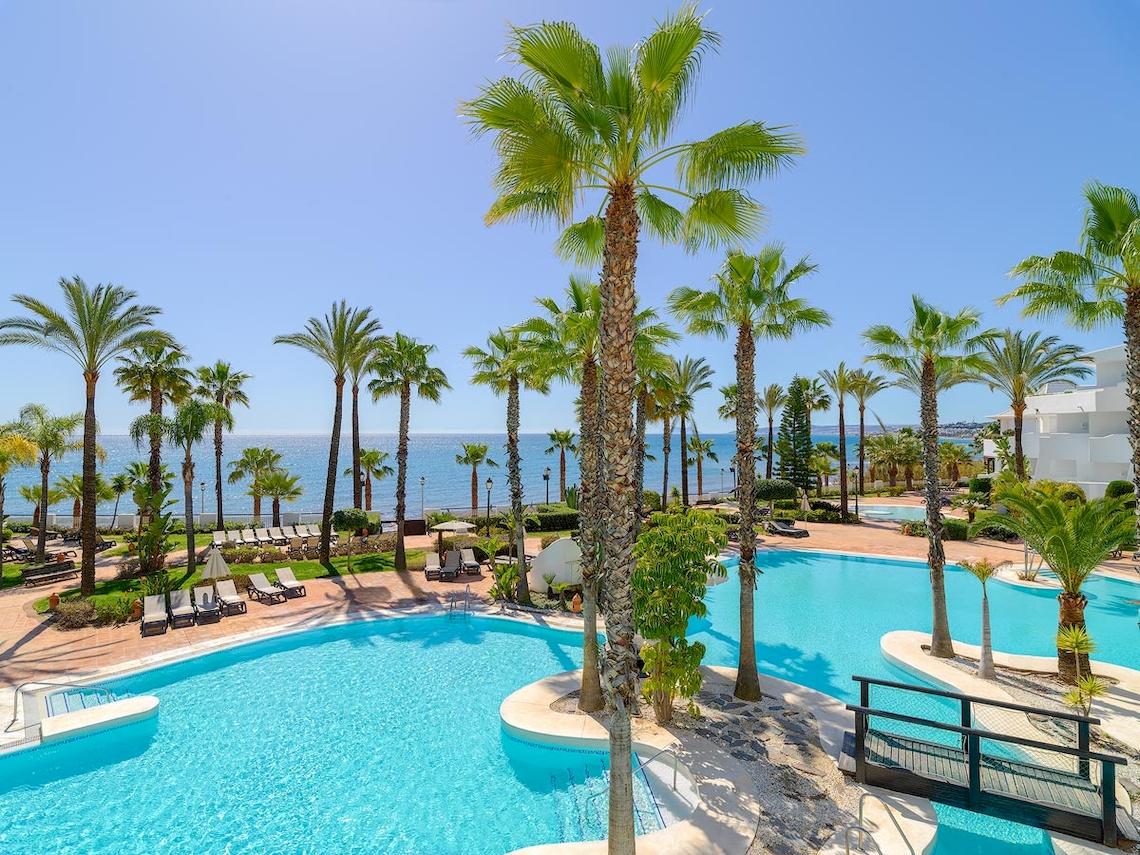 Außenpool des H10 Estepona Palace mit Palmen und Blick auf das Meer